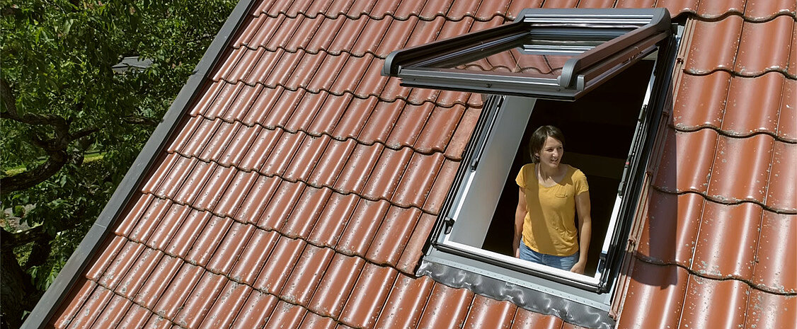 Frau schaut aus einem Dachfenster